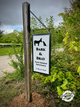 Load image into Gallery viewer, Sign for Bark & Bray Farm Animal Sanctuary on a wooden post with greenery in the background.